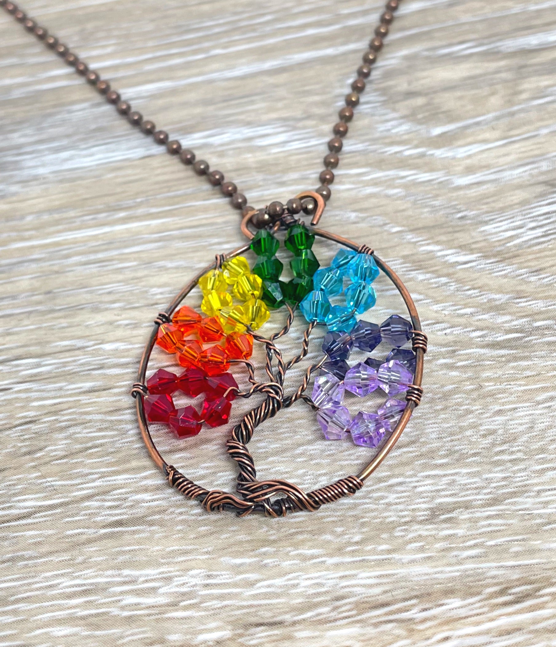 Wire Wrapped Rainbow Tree of Life Pendant featuring colorful glass crystals and oxidized copper wire on an 18-inch ball chain.