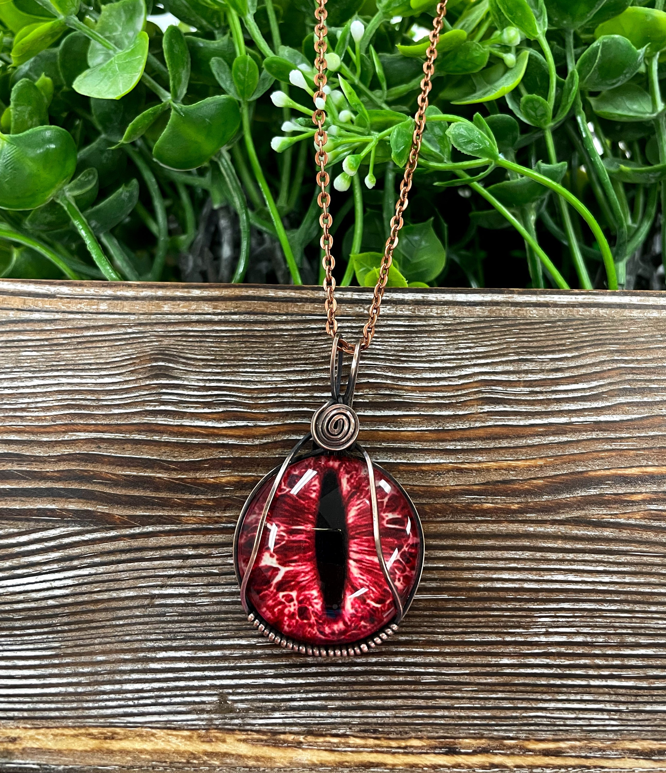 Wire Wrapped Red Dragon Eye Glass Cabochon Pendant with oxidized copper wire on a 21-inch cord, showcasing a striking red dragon eye design.