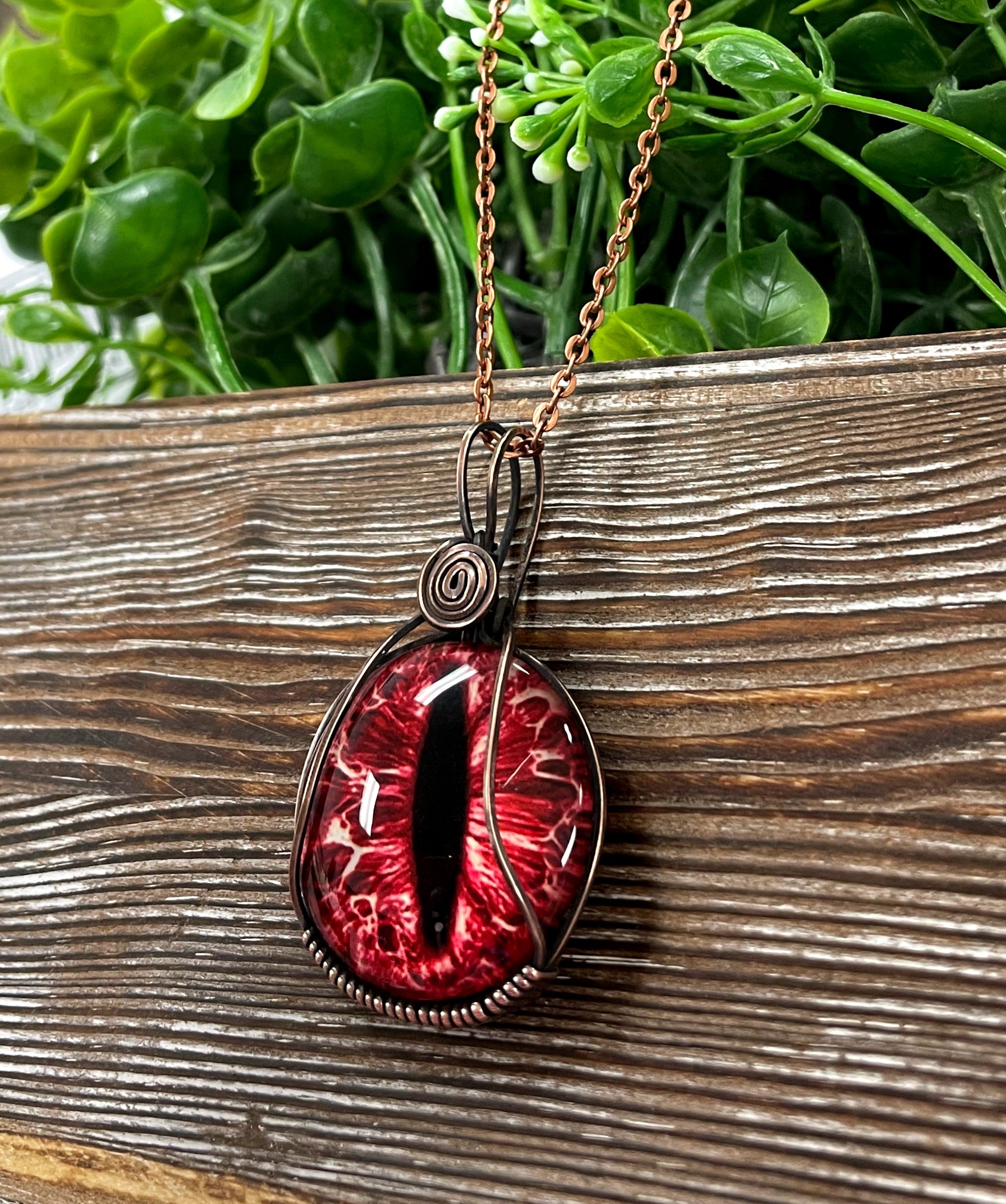 Wire Wrapped Red Dragon Eye Glass Cabochon Pendant with oxidized copper wire on a 21-inch cord, showcasing a striking red dragon eye design.