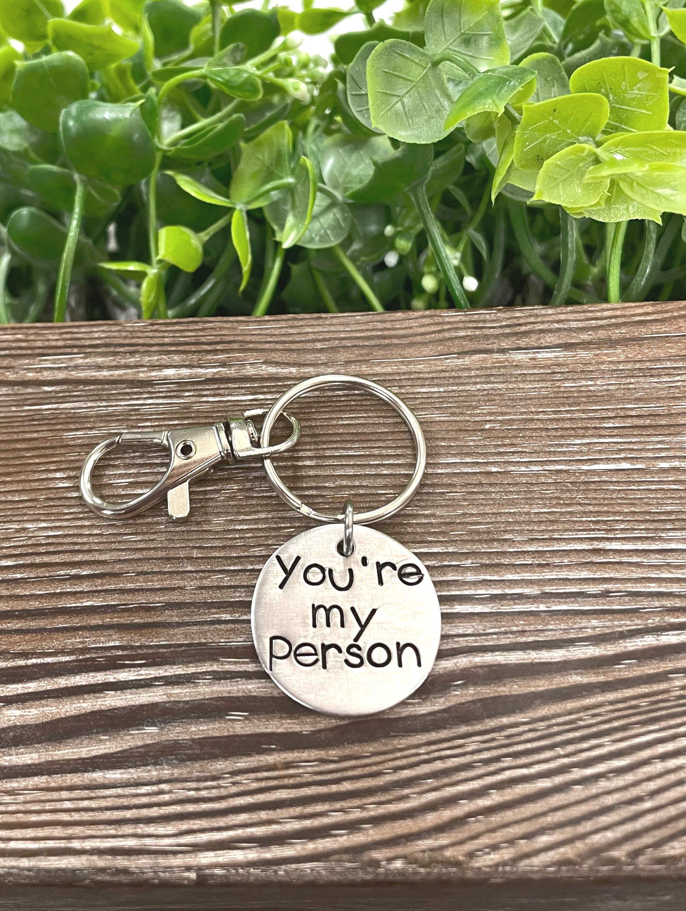 A hand-stamped keychain featuring the phrase 'You’re my Person', showcasing unique letter spacing and depth.