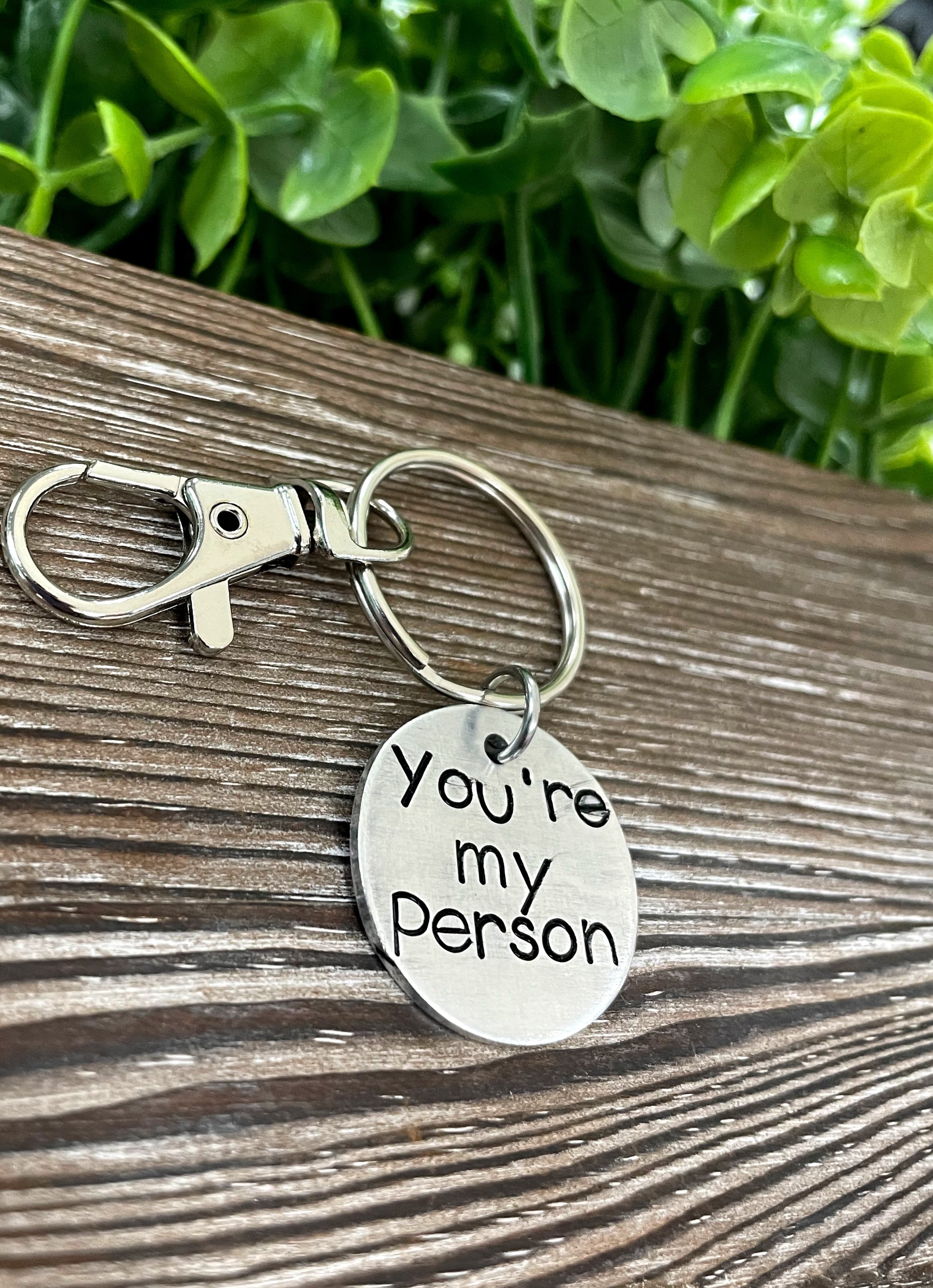 A hand-stamped keychain featuring the phrase 'You’re my Person', showcasing unique letter spacing and depth.