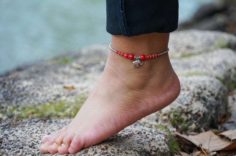 A beautifully handcrafted Red Elephant Pendant Boho Silver Anklet featuring silver bells and pressed cotton chords, perfect for bohemian style lovers.