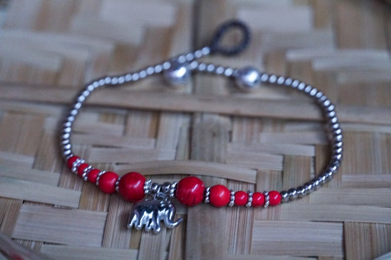 A beautifully handcrafted Red Elephant Pendant Boho Silver Anklet featuring silver bells and pressed cotton chords, perfect for bohemian style lovers.