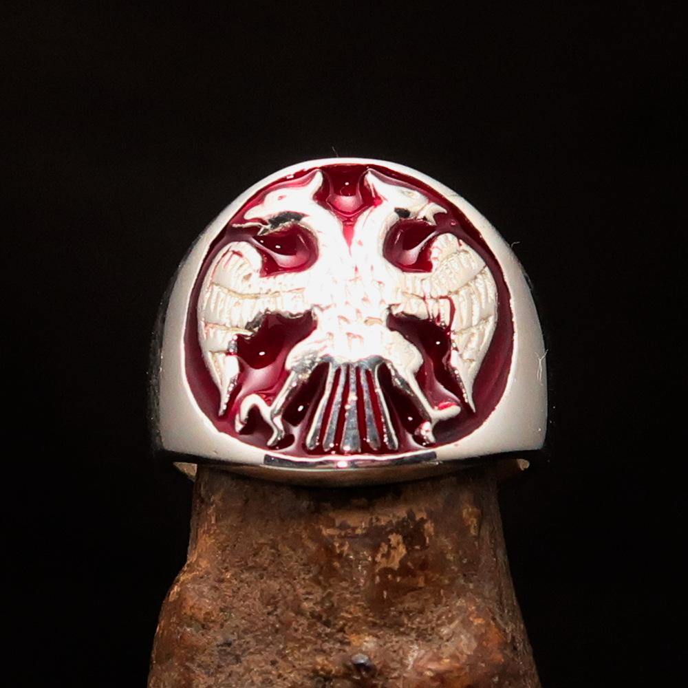 A beautifully crafted sterling silver men's ring featuring a twin head eagle design with red enamel detailing, showcasing its intricate craftsmanship.