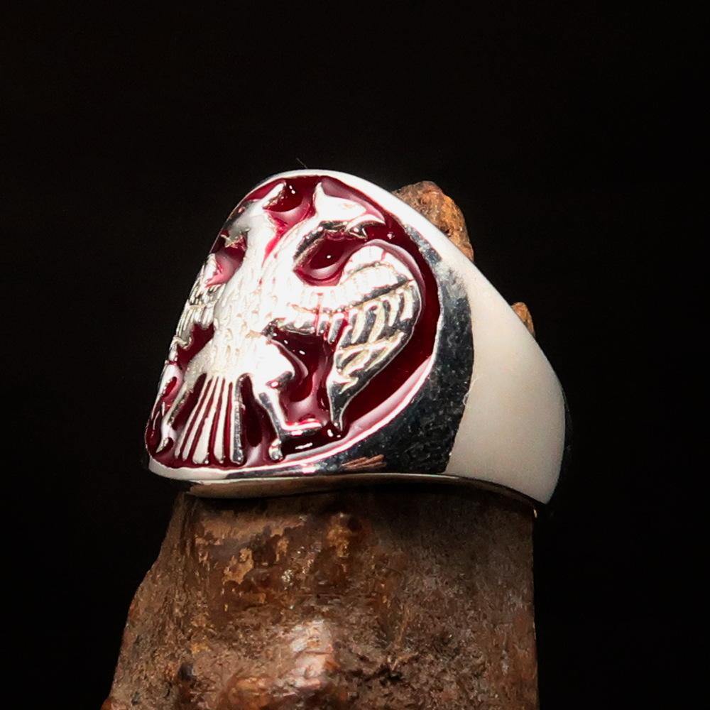 A beautifully crafted sterling silver men's ring featuring a twin head eagle design with red enamel detailing, showcasing its intricate craftsmanship.