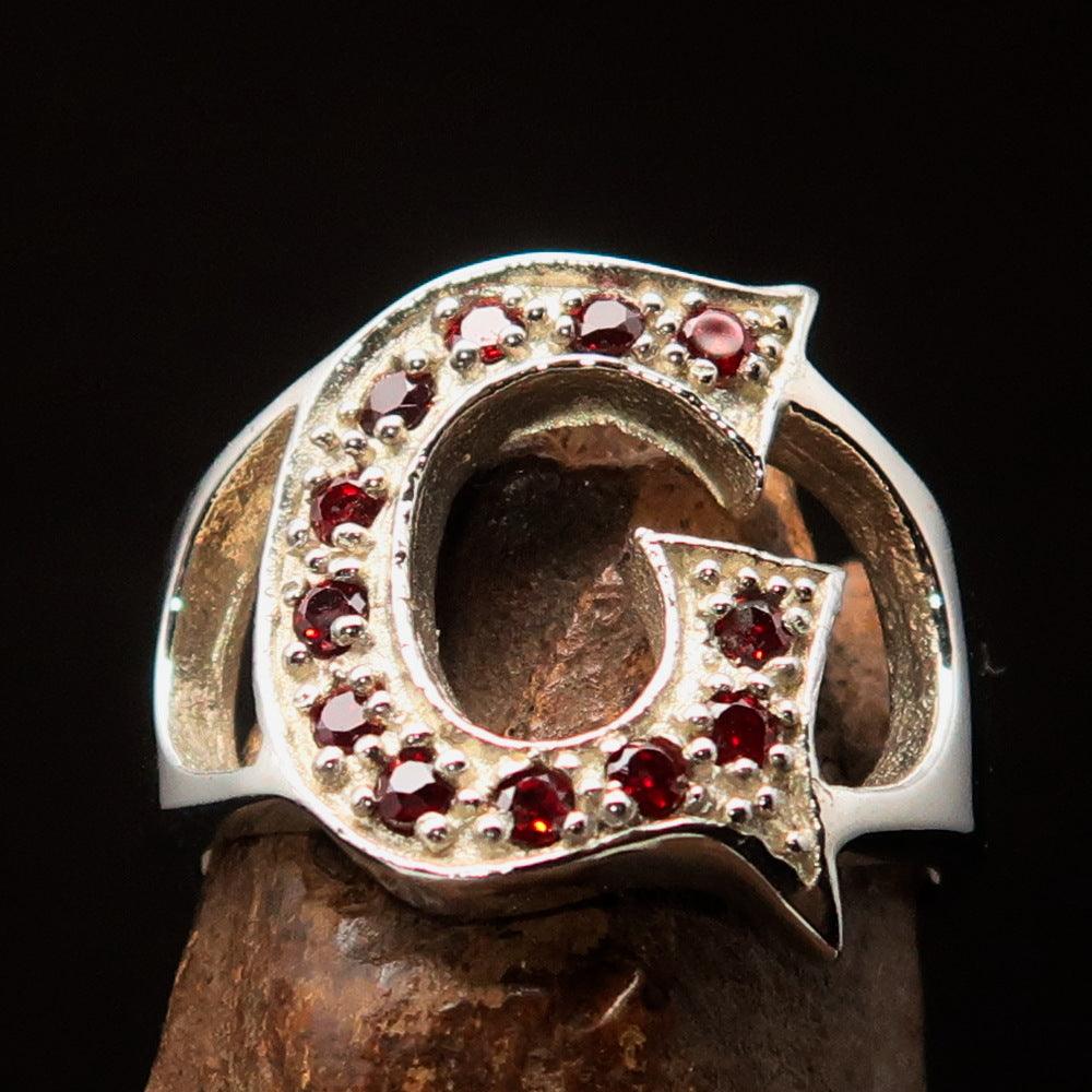 A beautifully crafted sterling silver Initial Ring featuring a bold letter G adorned with 12 vibrant red Cubic Zirconias, showcasing its elegance.