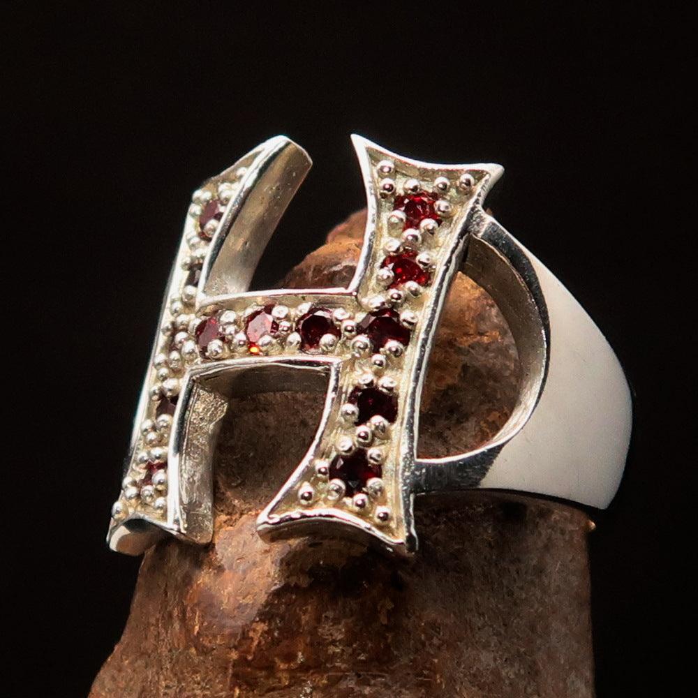 A beautifully crafted sterling silver ring featuring a bold letter H adorned with 13 red cubic zirconias, showcasing luxury and elegance.