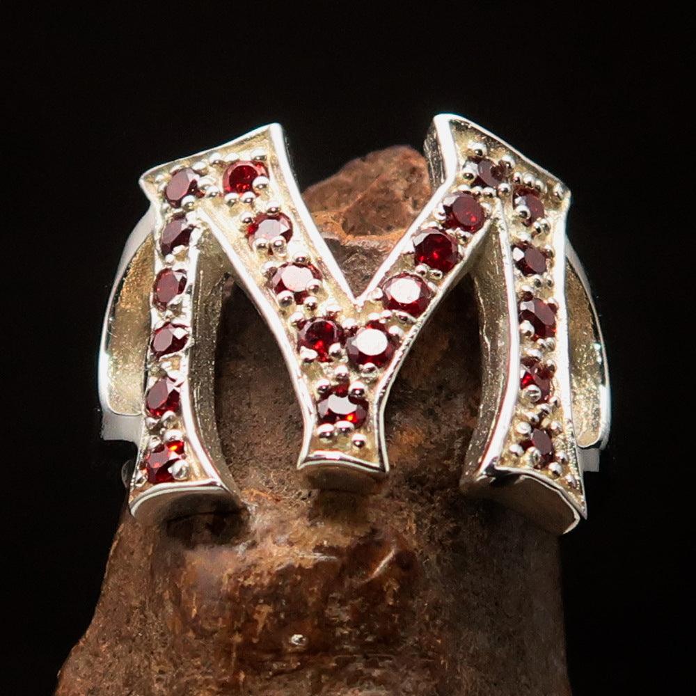 A beautifully crafted sterling silver ring featuring a bold letter M adorned with 21 red cubic zirconia stones, showcasing elegance and luxury.