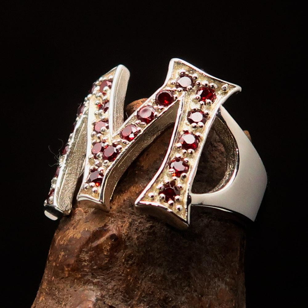 A beautifully crafted sterling silver ring featuring a bold letter M adorned with 21 red cubic zirconia stones, showcasing elegance and luxury.