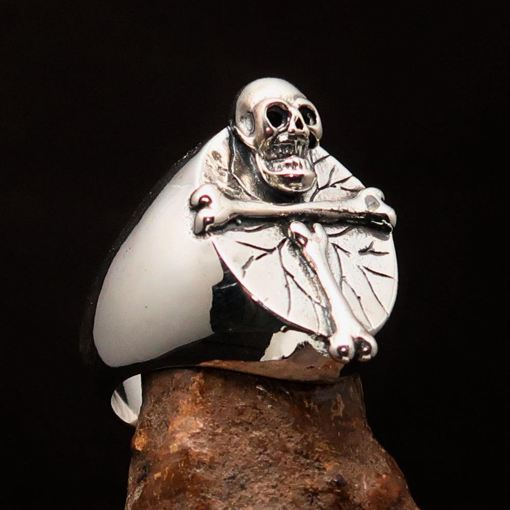 Men's sterling silver ring featuring a bone cross and R.I.P skull design, showcasing intricate craftsmanship and a polished finish.