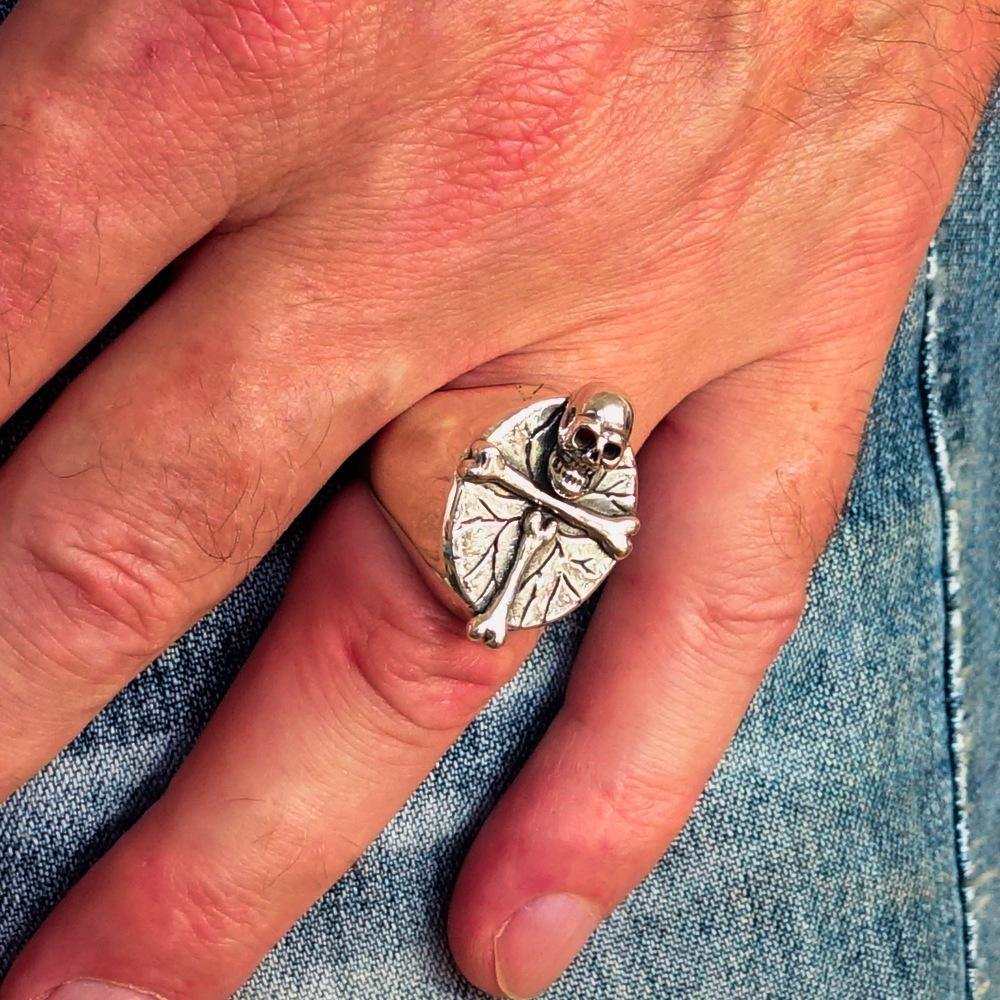 Men's sterling silver ring featuring a bone cross and R.I.P skull design, showcasing intricate craftsmanship and a polished finish.