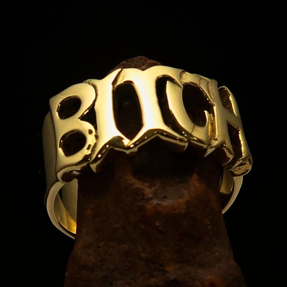 A high polished solid brass ring featuring the word 'Bitch', measuring 12 mm wide, showcasing its elegant design.