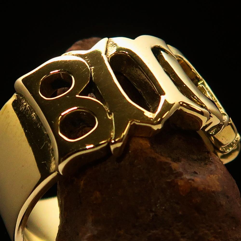 A high polished solid brass ring featuring the word 'Bitch', measuring 12 mm wide, showcasing its elegant design.