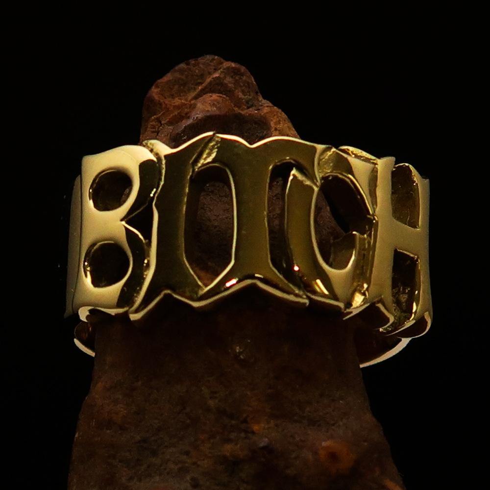 A high polished solid brass ring featuring the word 'Bitch', measuring 12 mm wide, showcasing its elegant design.