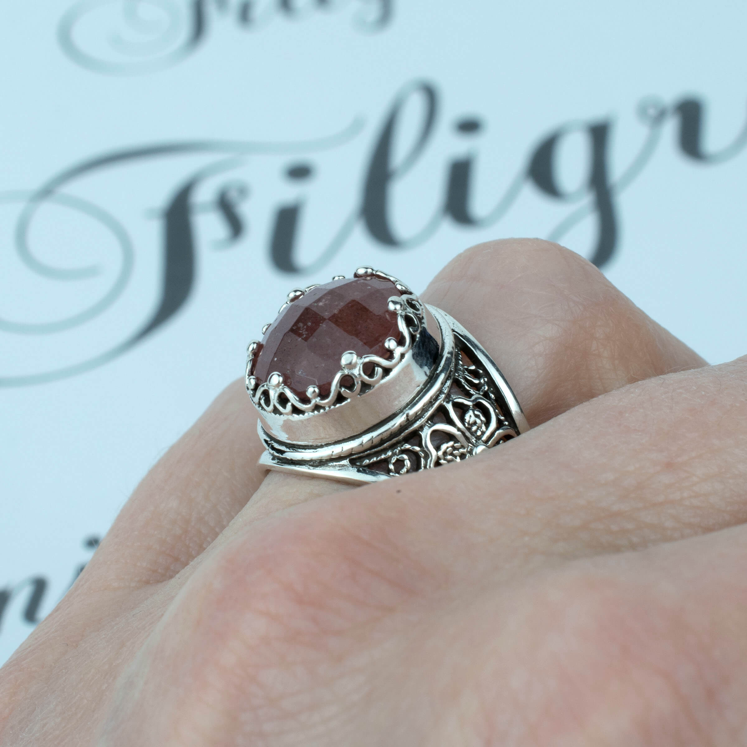 A stunning sterling silver filigree ring featuring a 12mm cherry quartz gemstone, elegantly designed with intricate metalwork.