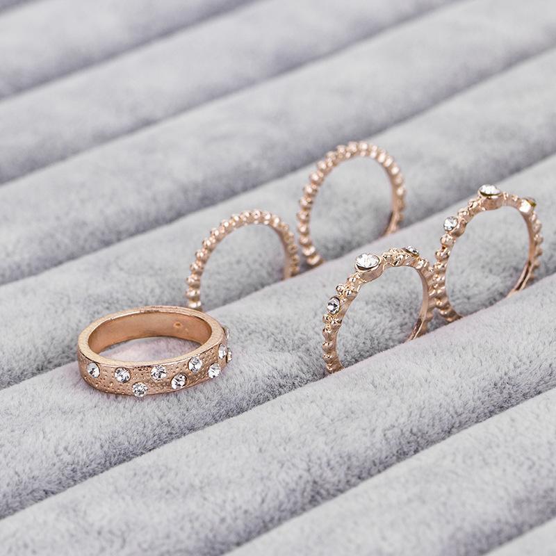 Five Piece Rose Gold Ring Set featuring a thicker band with crystals and four thin bands, elegantly displayed.