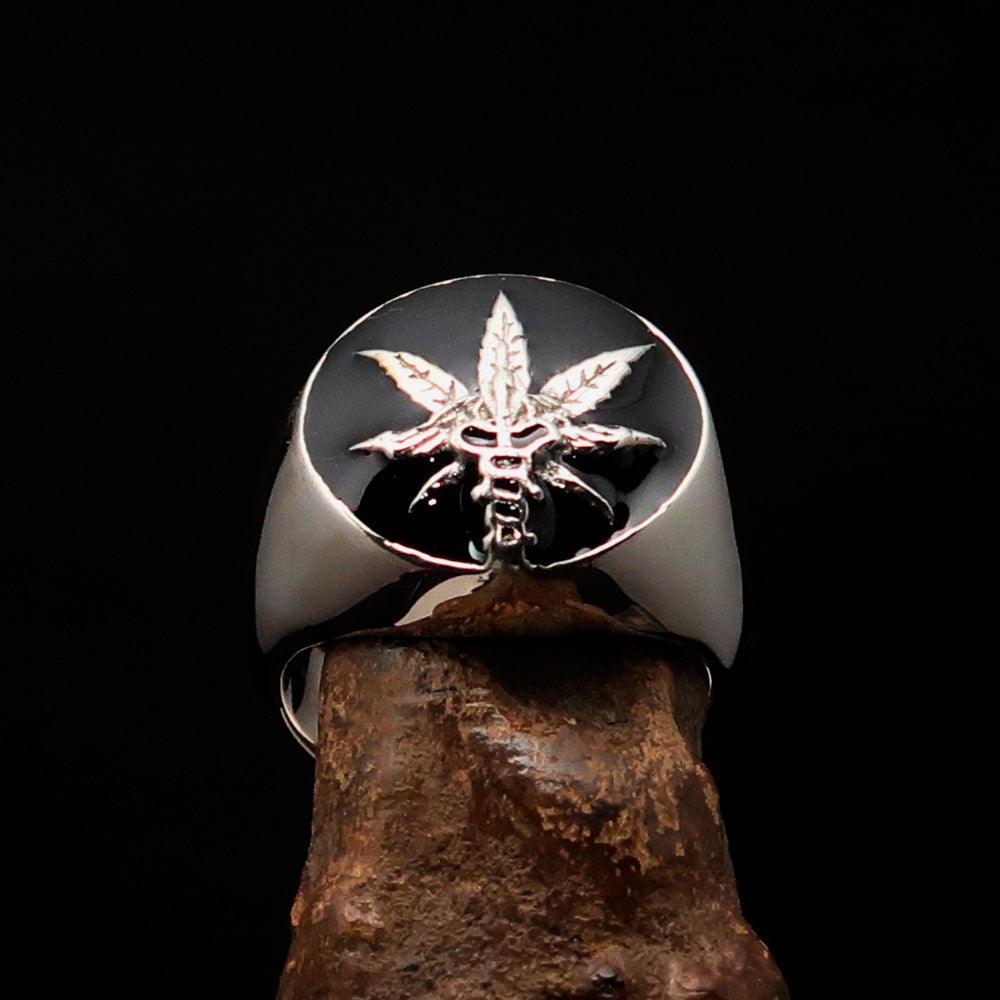 Men's sterling silver ring with a cannabis leaf symbol and black enamel finish, showcasing a polished design.