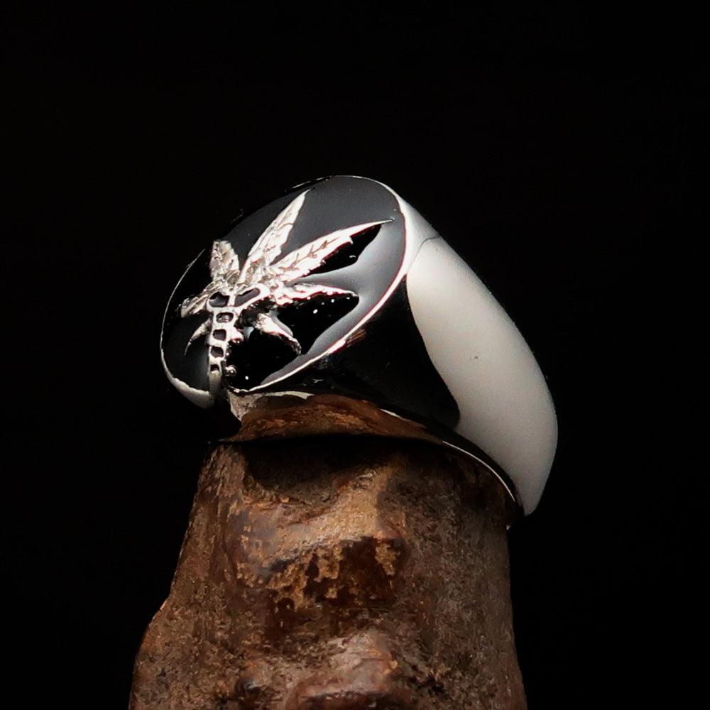 Men's sterling silver ring with a cannabis leaf symbol and black enamel finish, showcasing a polished design.