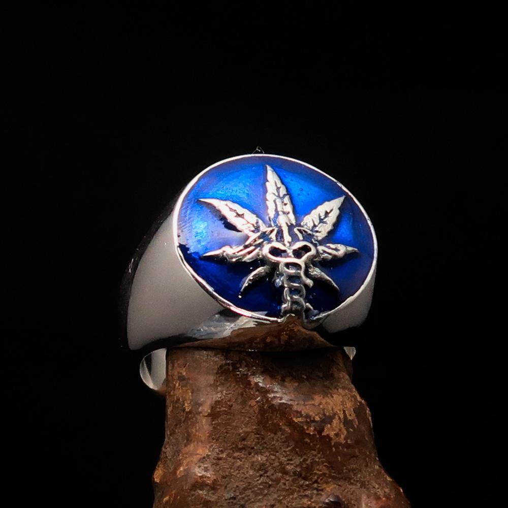 Men's sterling silver ring featuring a cannabis leaf symbol with blue enamel, showcasing a polished finish and unique design.