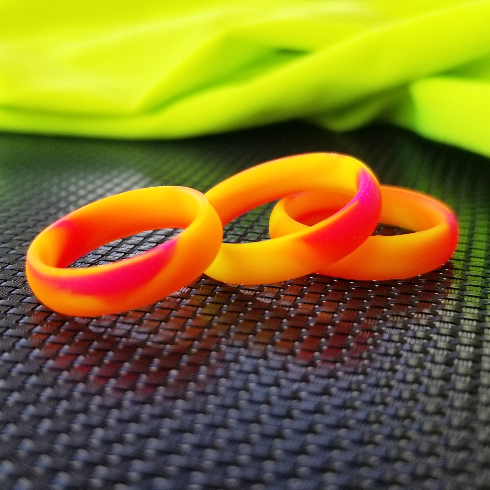 Vibrant neon orange, yellow, and pink swirl silicone ring with a sleek bevel design, showcasing its breathable and comfortable fit.