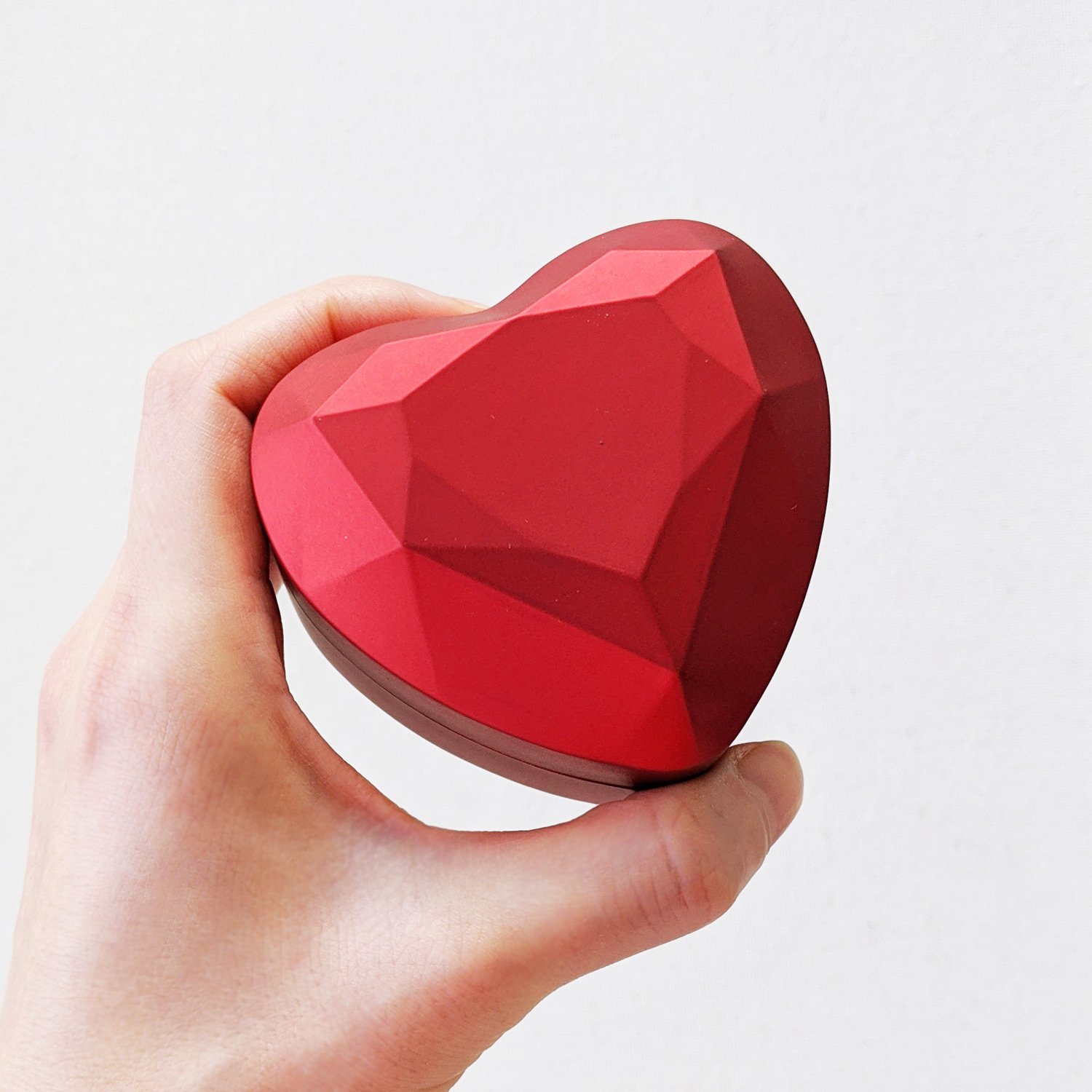 A luxurious red heart-shaped ring box with a satin finish and midnight blue velvet lining, designed to illuminate the ring inside when opened.