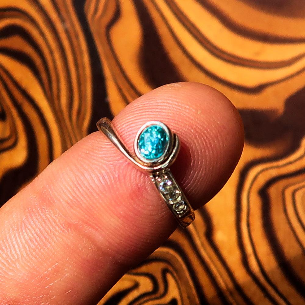 Sterling Silver Solitaire Band Ring featuring an oval cut blue Zircon and three cubic zirconia stones, polished to a mirror finish.