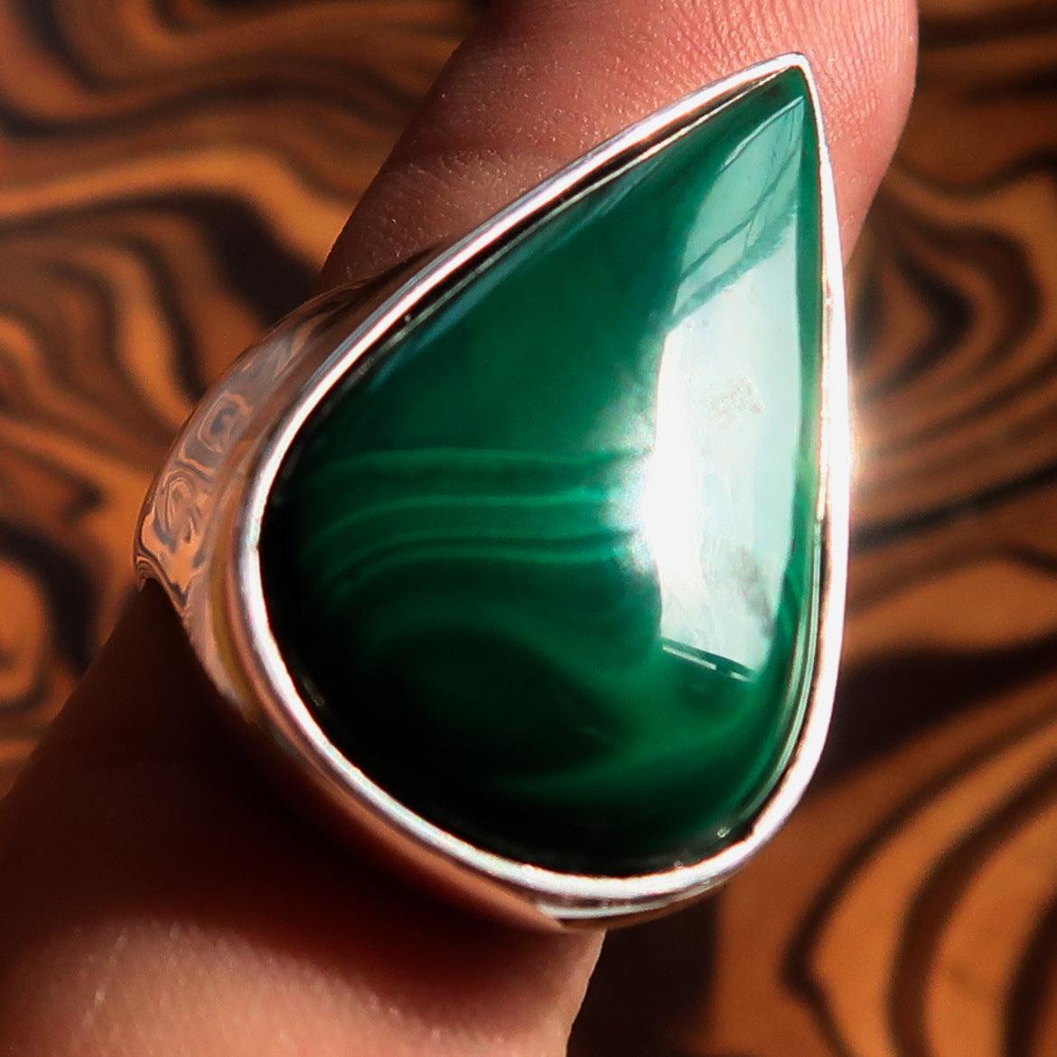 Tear shaped mirror polished sterling silver ring featuring a pear shaped green malachite stone, showcasing its elegant design and craftsmanship.