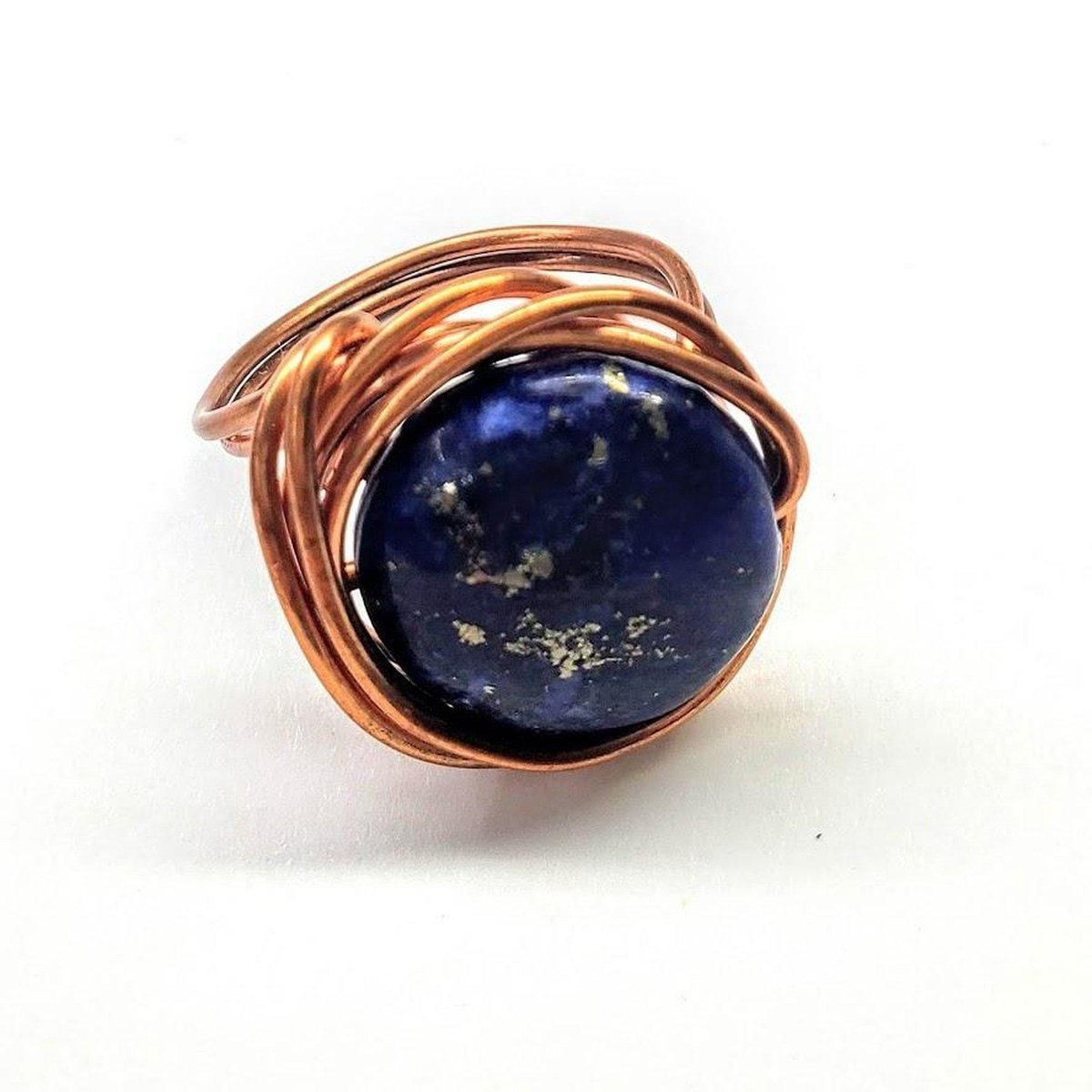 A handcrafted wire wrapped copper ring featuring a deep blue lapis lazuli coin bead, showcasing unique design and sparkling pyrite speckles.