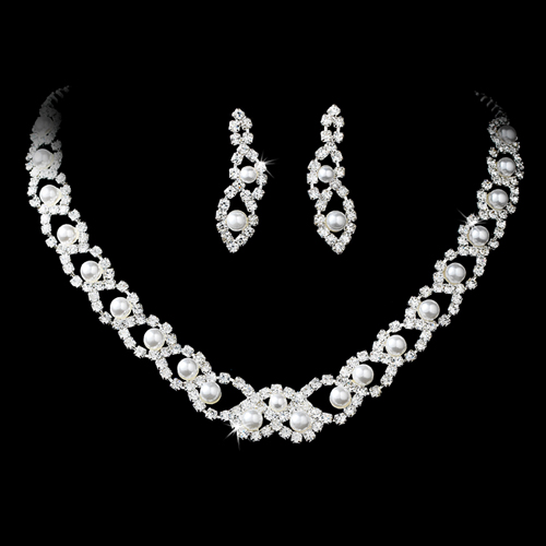 Elegant bridal wedding jewelry set featuring a pearl necklace and matching rhinestone earrings, displayed on a soft fabric background.