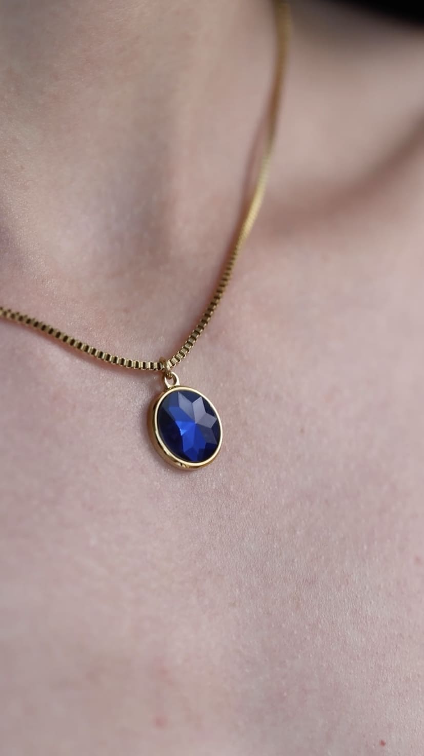 Facet Pendant Necklace JS.0005 featuring a blue faceted glass pendant on a gold plated stainless steel chain, elegantly displayed.