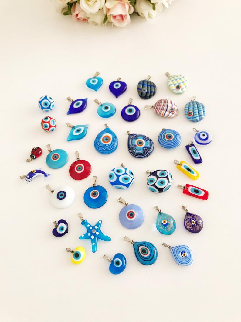 A collection of Handmade Murano Evil Eye Beads in blue and turquoise, showcasing intricate designs and vibrant colors.