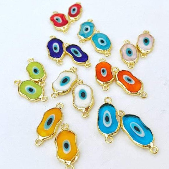 A collection of handmade Evil Eye Murano beads in various colors, showcasing their unique designs and 22K gold plated finish.