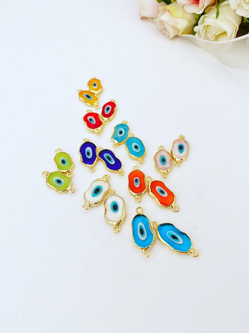 A collection of handmade Evil Eye Murano beads in various colors, showcasing their unique designs and 22K gold plated finish.