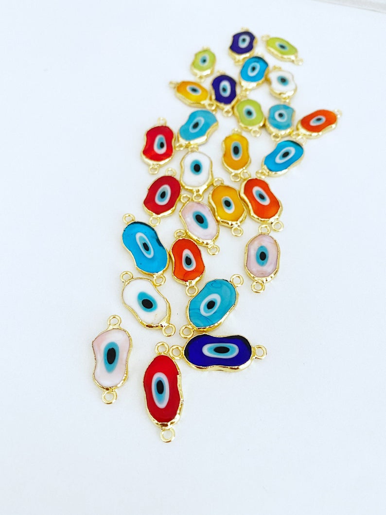 A collection of handmade Evil Eye Murano beads in various colors, showcasing their unique designs and 22K gold plated finish.