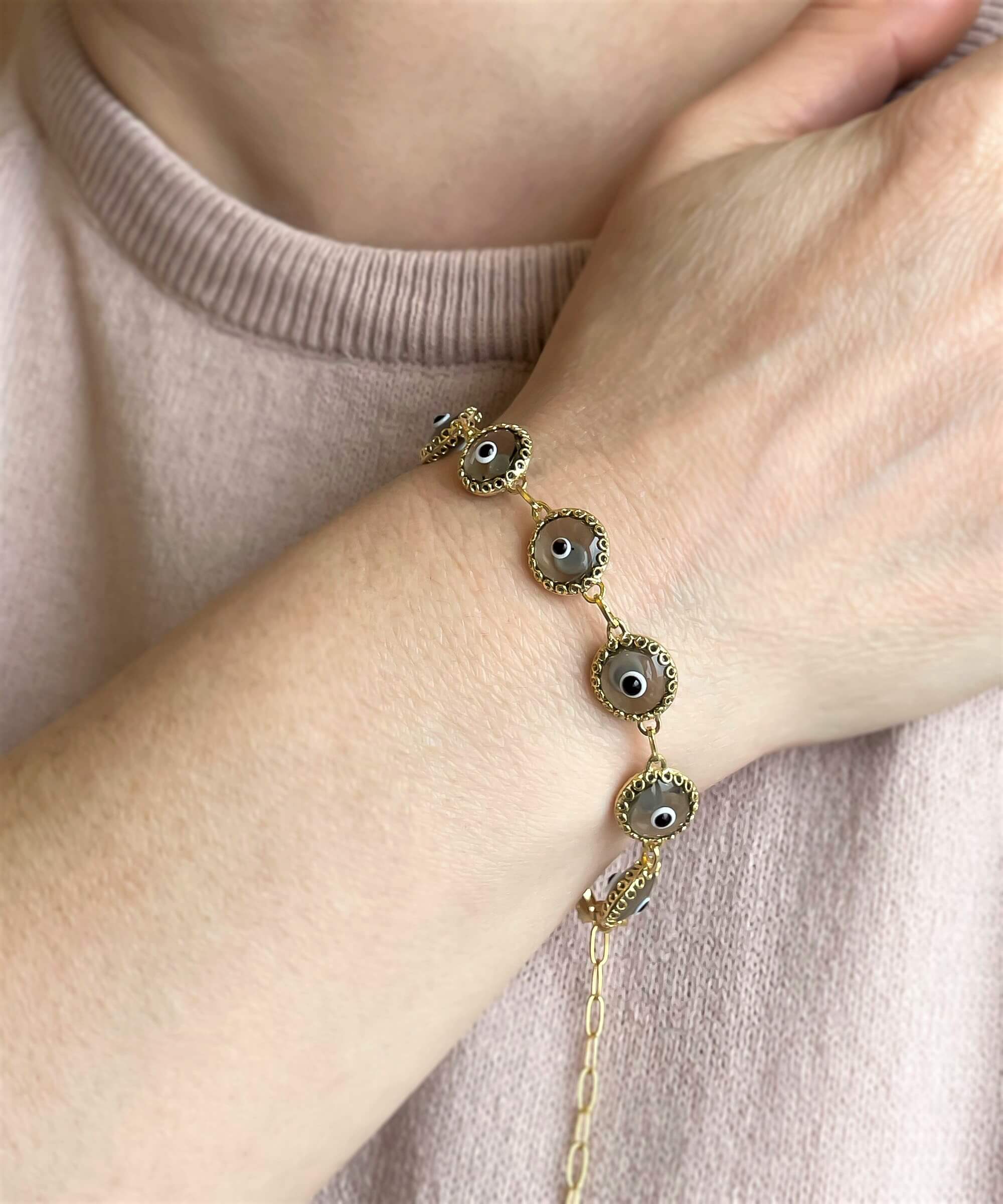 Elegant gold plated sterling silver link bracelet featuring 10 smokey evil eye beads, designed for women with a lobster claw clasp.