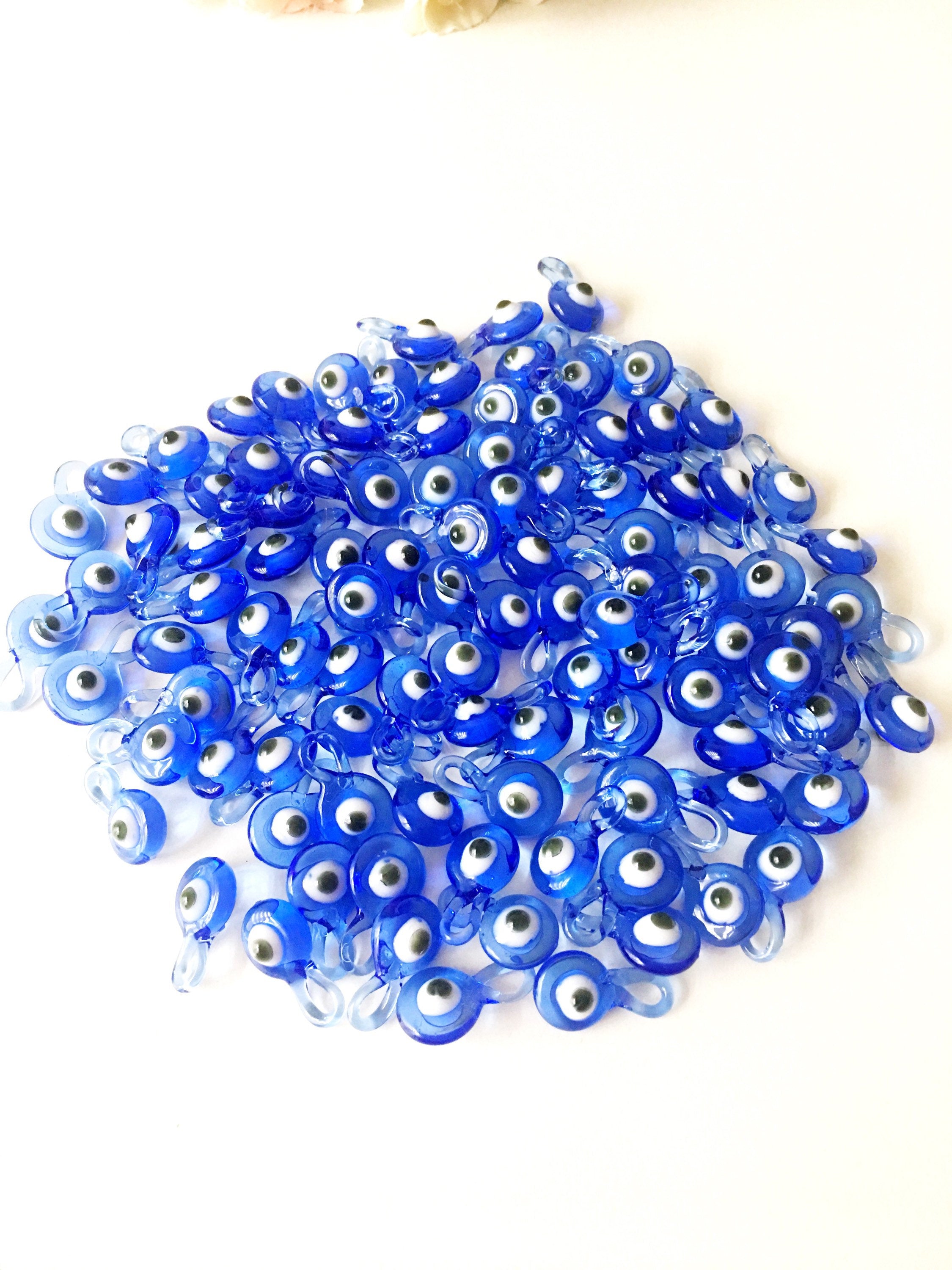 A collection of 10 blue glass evil eye charms, featuring intricate designs and metal hooks, perfect for baby shower favors.