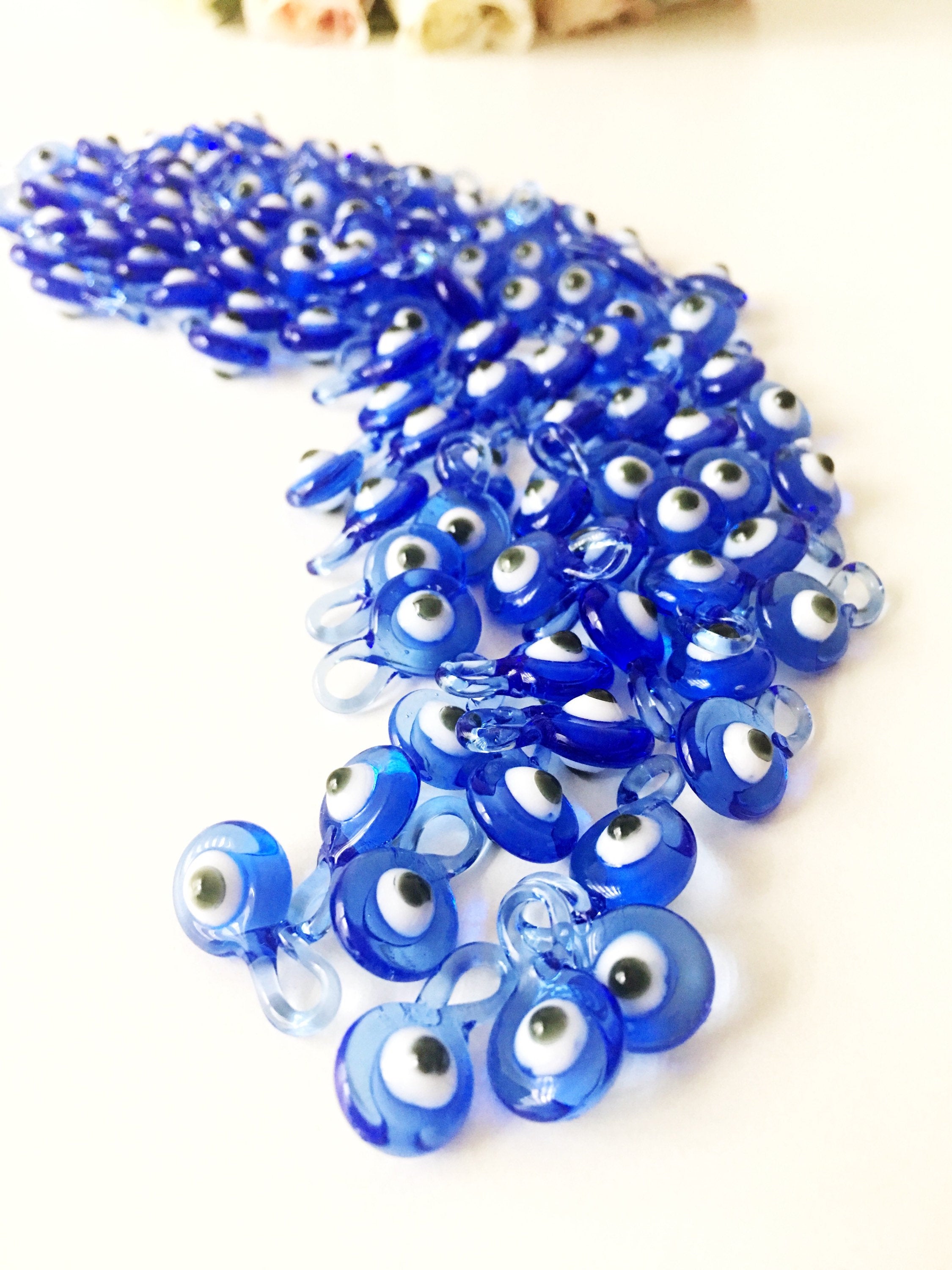 A collection of 10 blue glass evil eye charms, featuring intricate designs and metal hooks, perfect for baby shower favors.