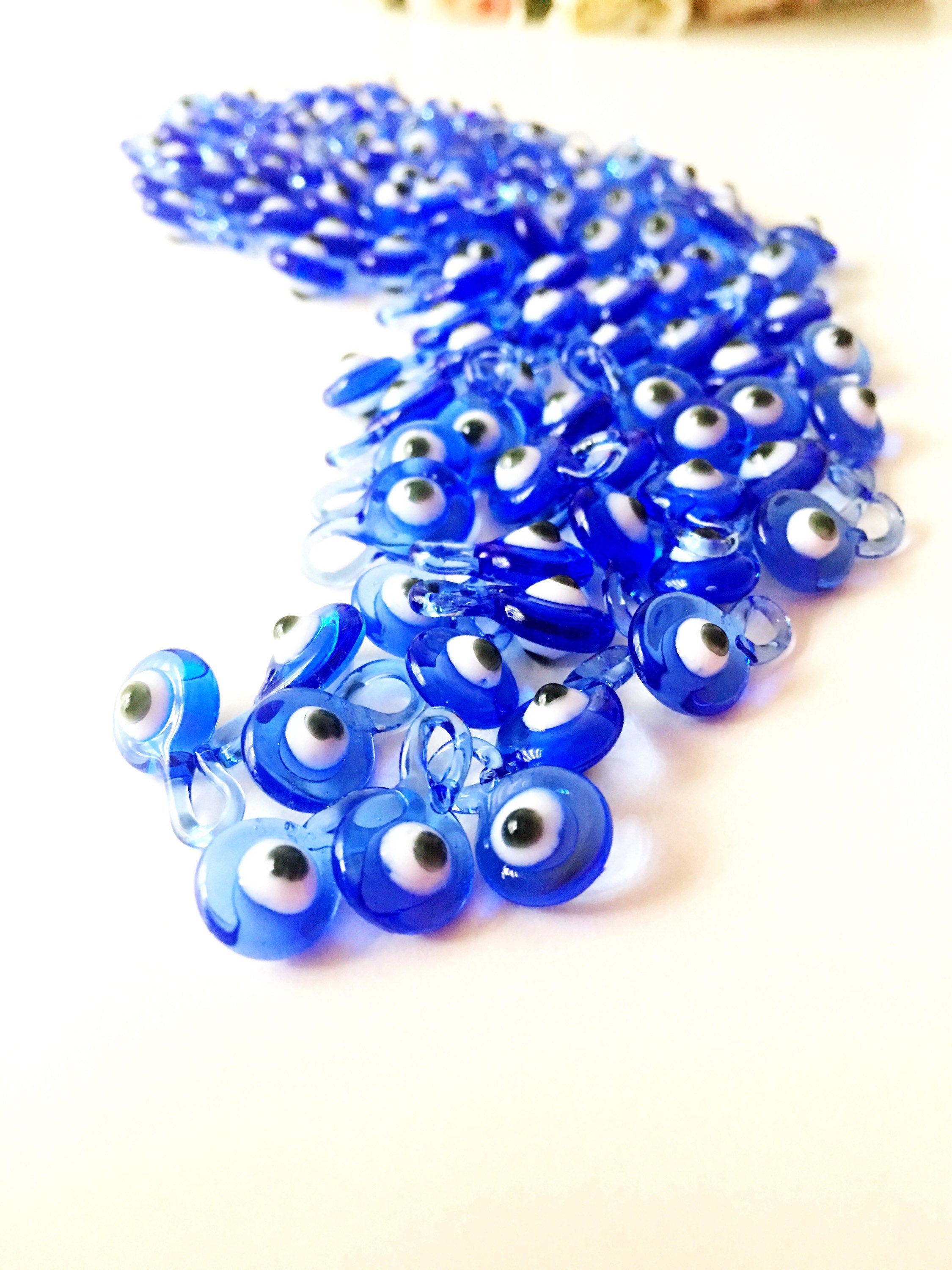 A collection of 10 blue glass evil eye charms, featuring intricate designs and metal hooks, perfect for baby shower favors.