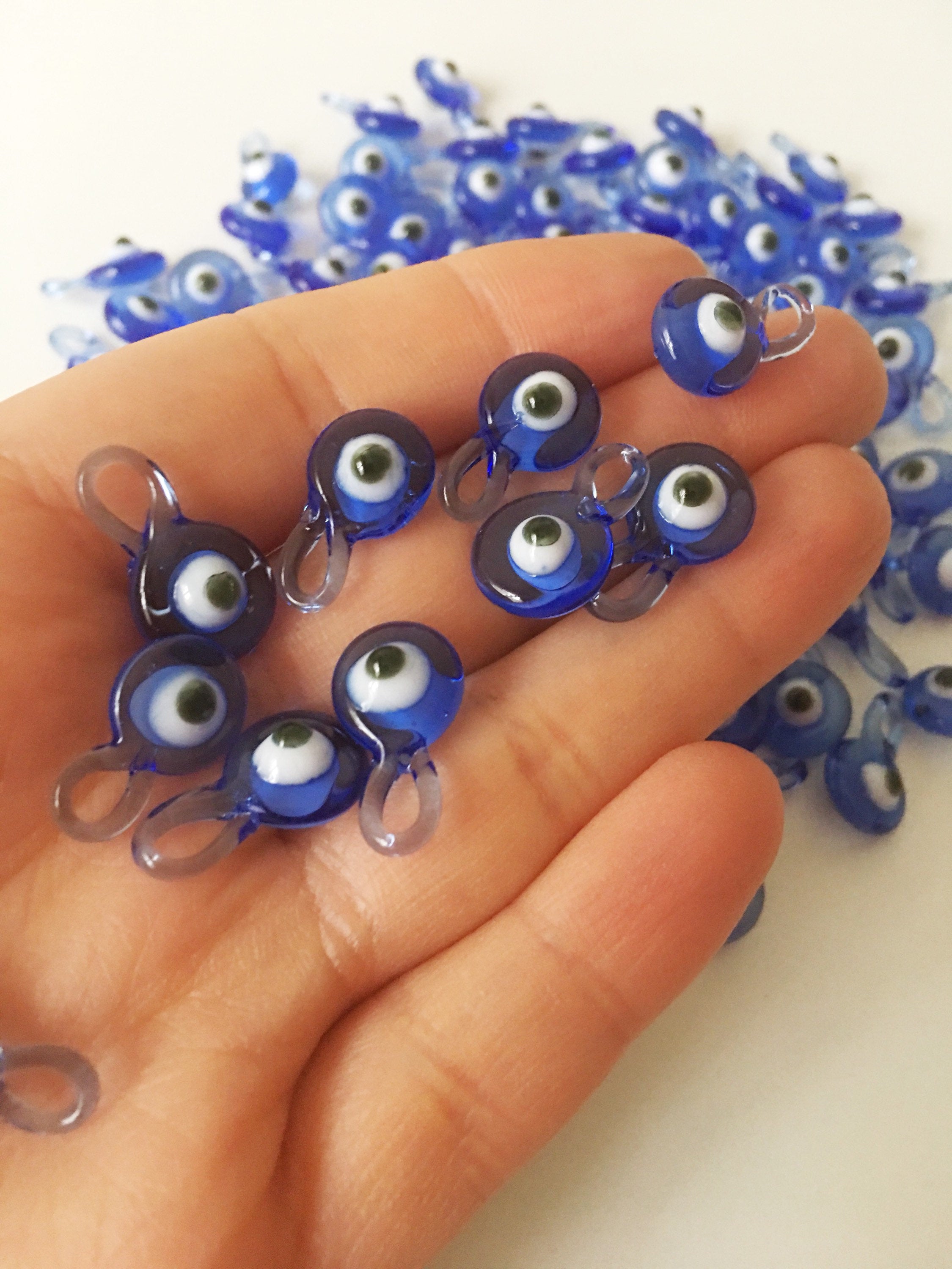 A collection of 10 blue glass evil eye charms, featuring intricate designs and metal hooks, perfect for baby shower favors.