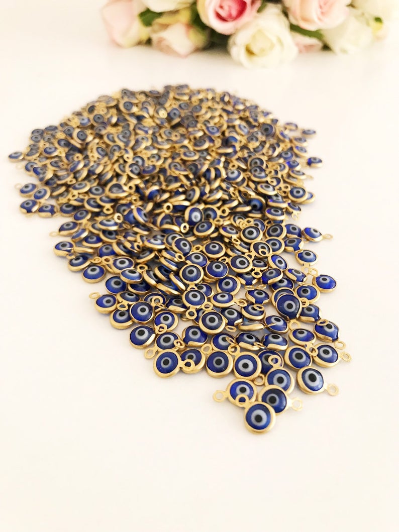 A bulk set of 100 blue evil eye beads, each 6mm in diameter, made from glass with stainless steel gold accents, showcasing both-sided charm design.