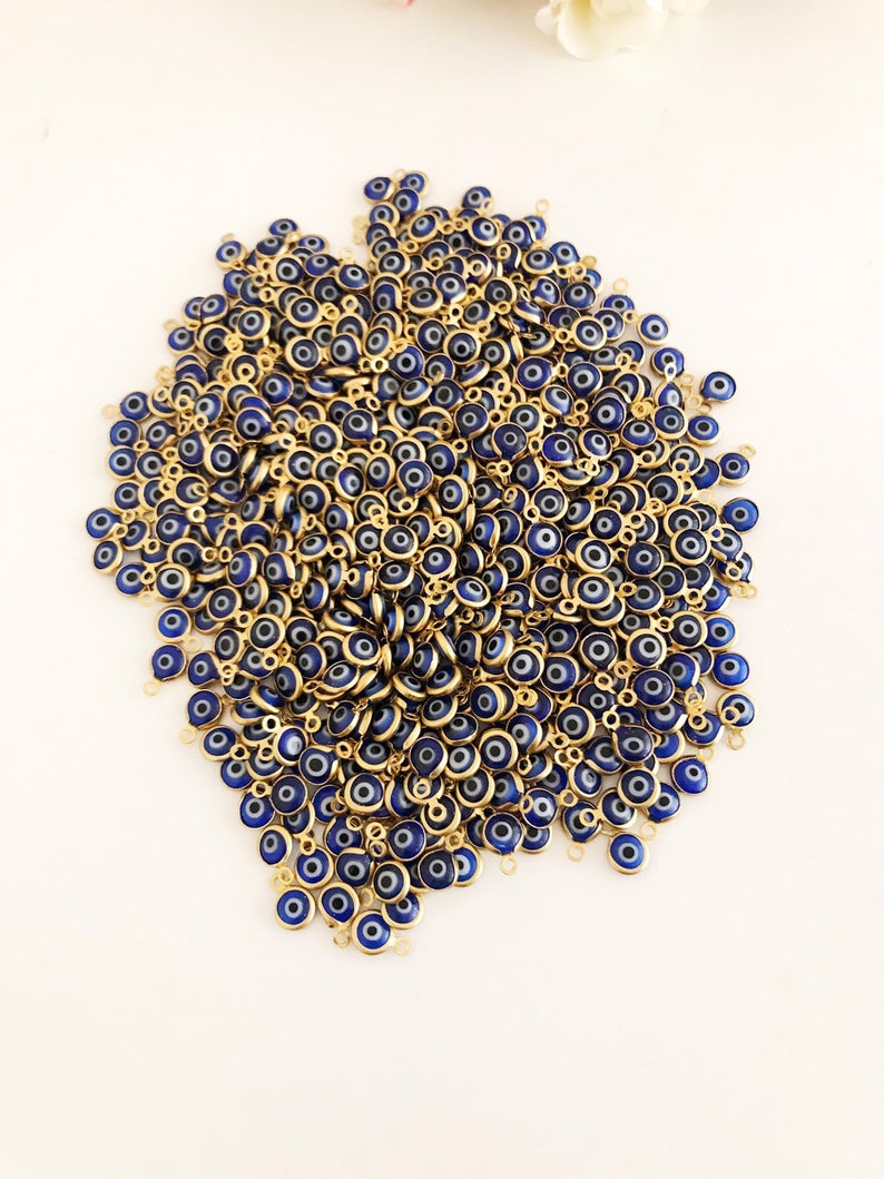 A bulk set of 100 blue evil eye beads, each 6mm in diameter, made from glass with stainless steel gold accents, showcasing both-sided charm design.