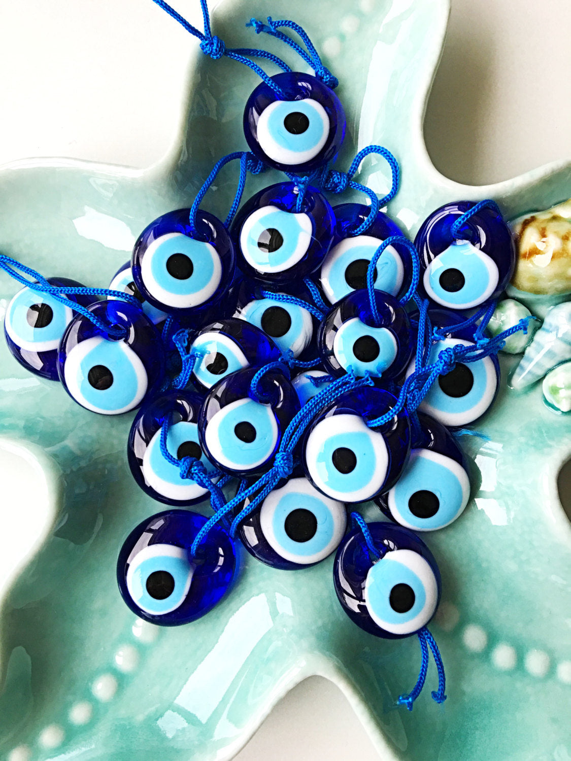 A collection of 100 blue evil eye beads made of glass, featuring blue ropes for hanging, symbolizing protection and good luck.