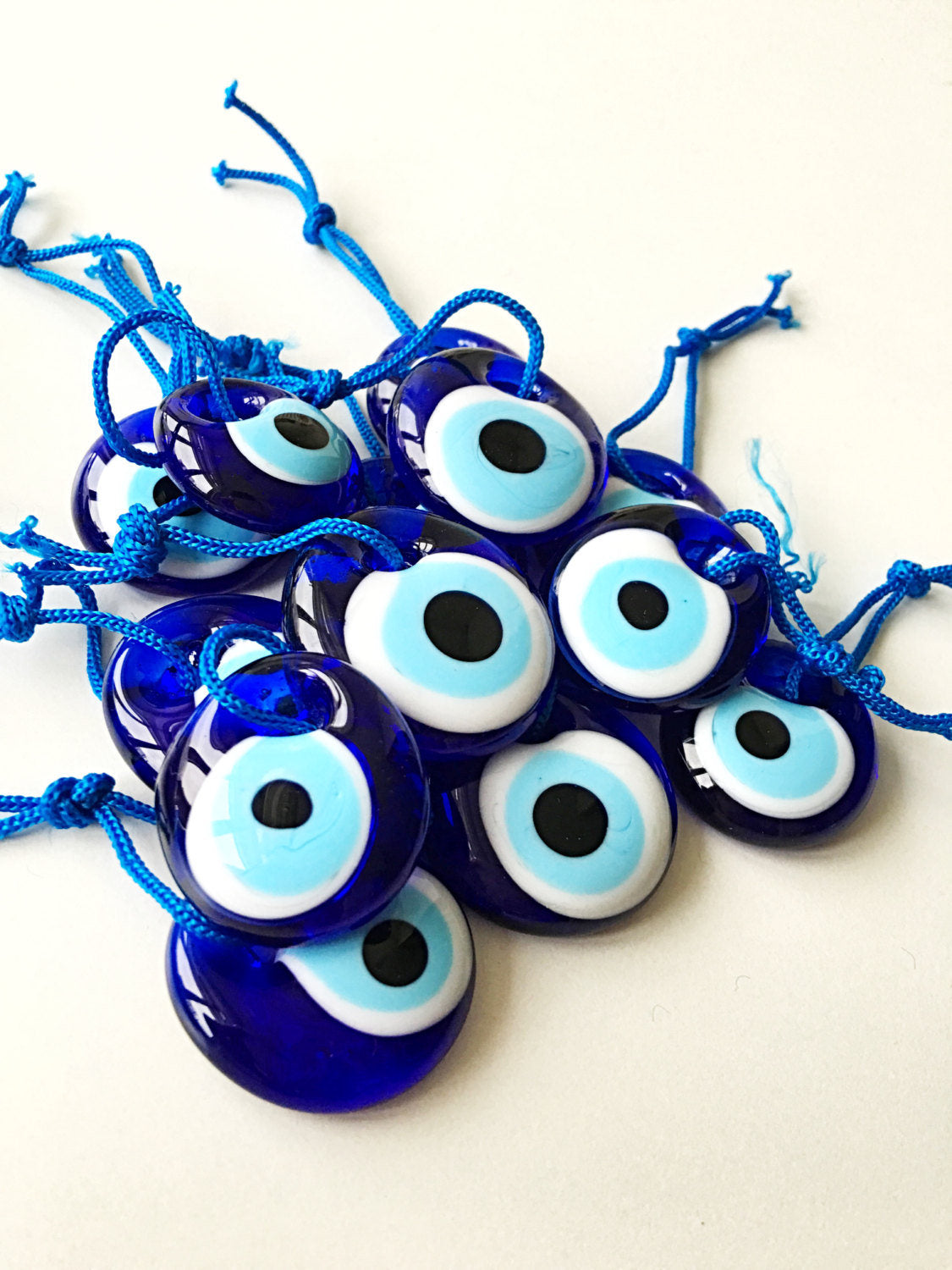 A collection of 100 blue evil eye beads made of glass, featuring blue ropes for hanging, symbolizing protection and good luck.