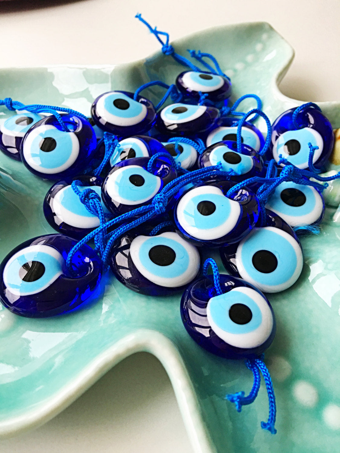 A collection of 100 blue evil eye beads made of glass, featuring blue ropes for hanging, symbolizing protection and good luck.