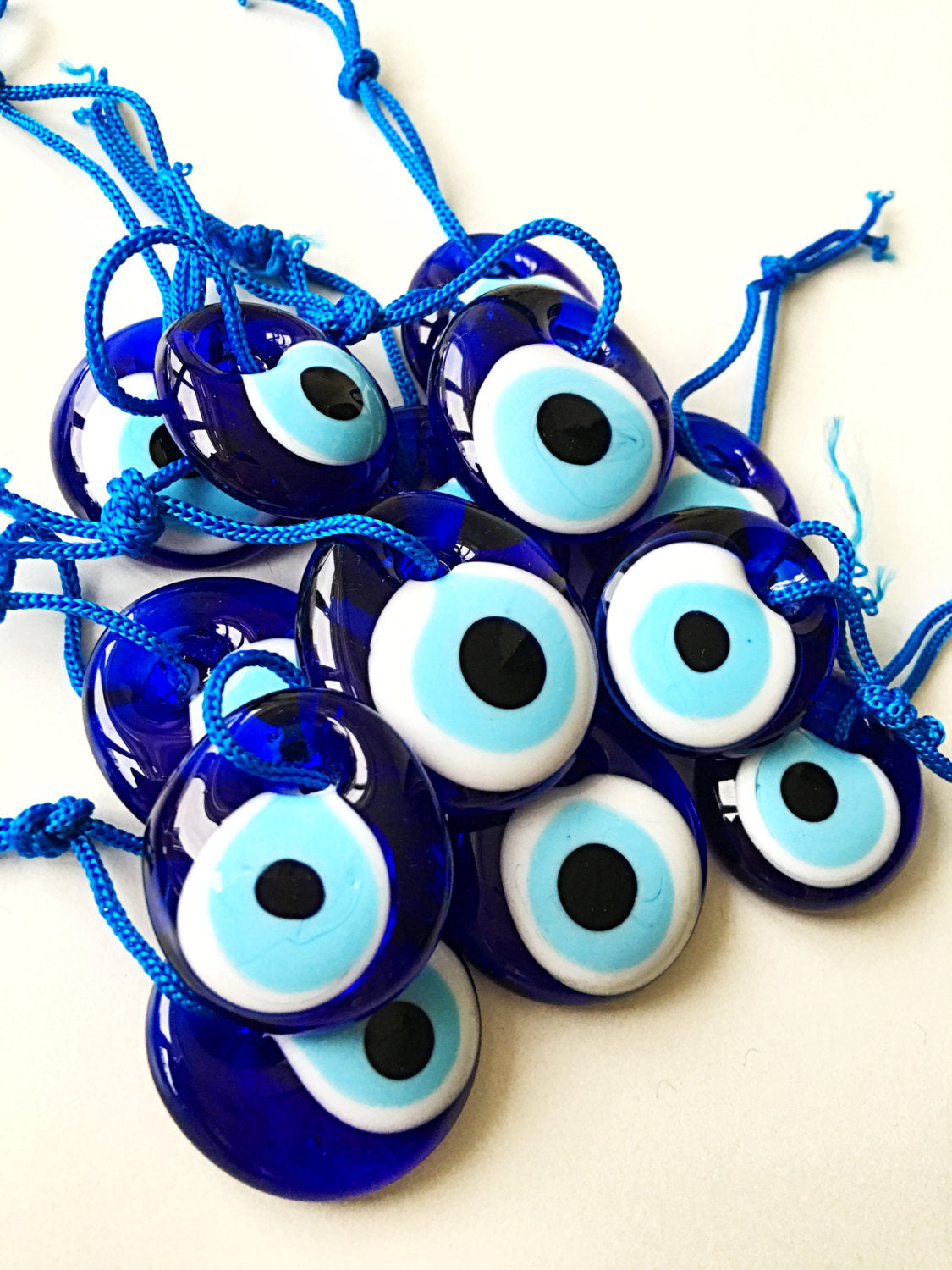 A collection of 100 blue evil eye beads made of glass, featuring blue ropes for hanging, symbolizing protection and good luck.