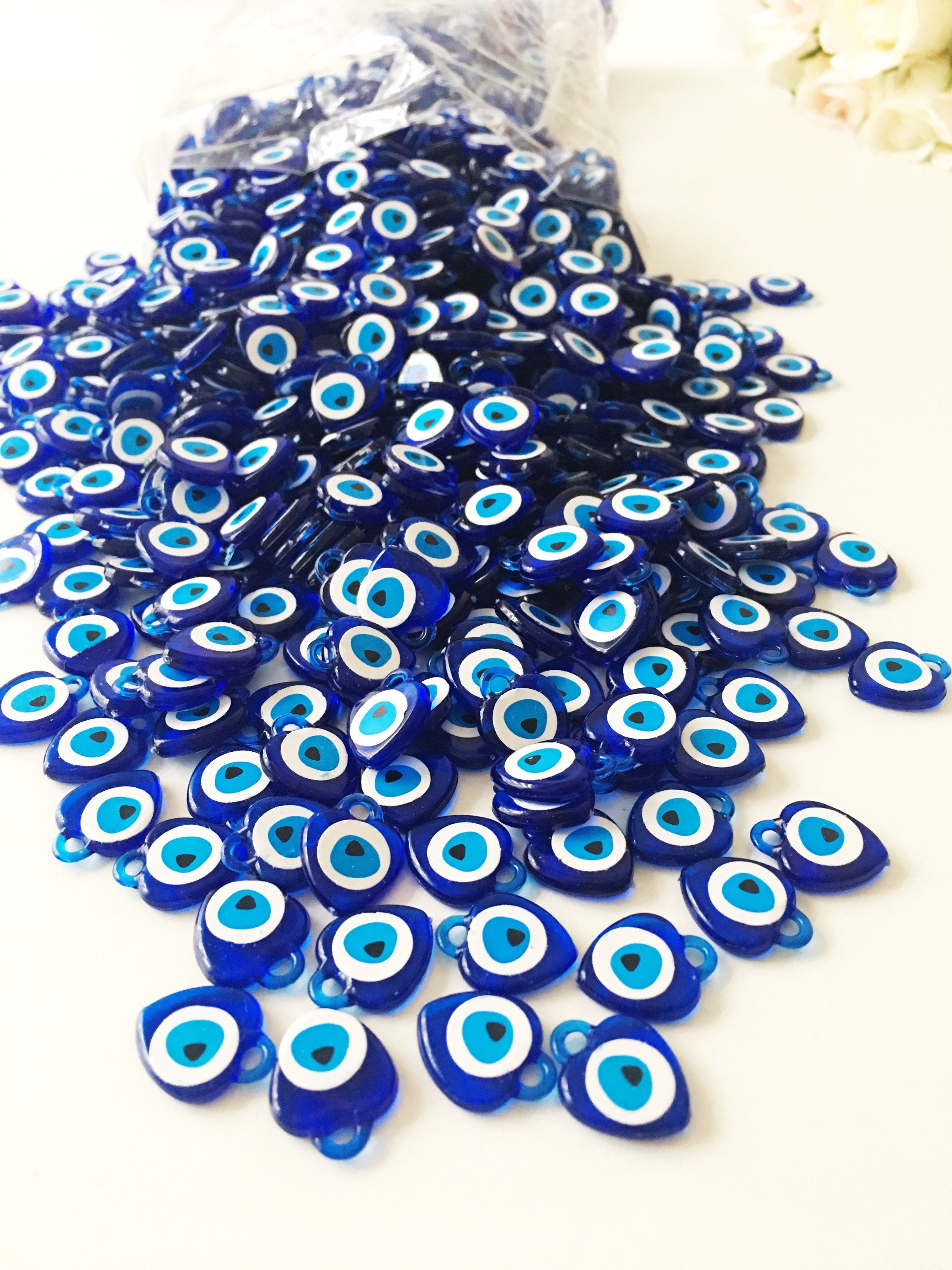 A collection of 100 blue evil eye charms made from resin, showcasing their vibrant color and intricate design, perfect for wedding and party favors.