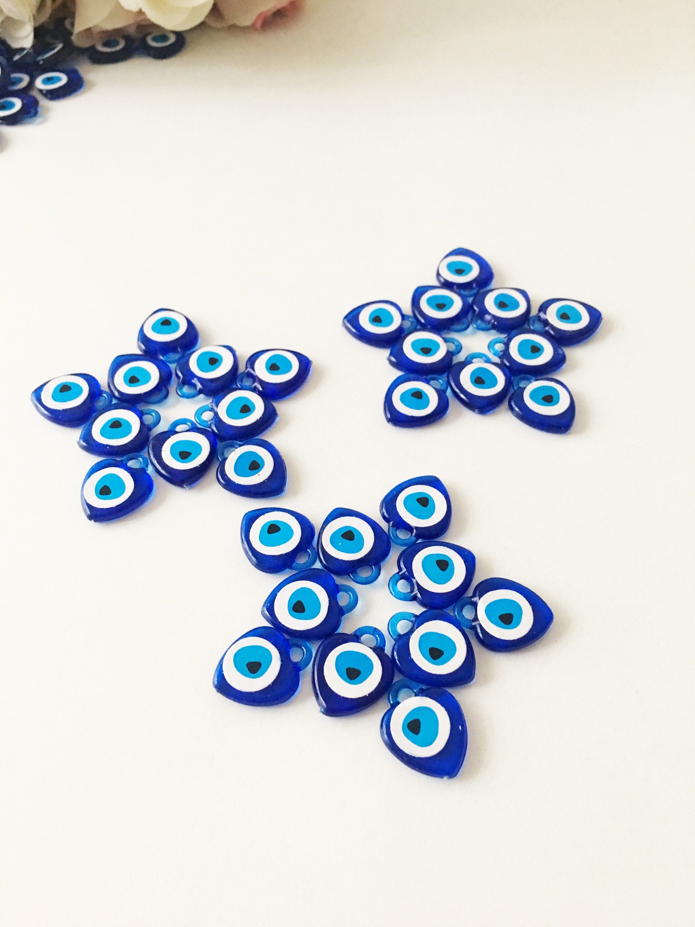 A collection of 100 blue evil eye charms made from resin, showcasing their vibrant color and intricate design, perfect for wedding and party favors.