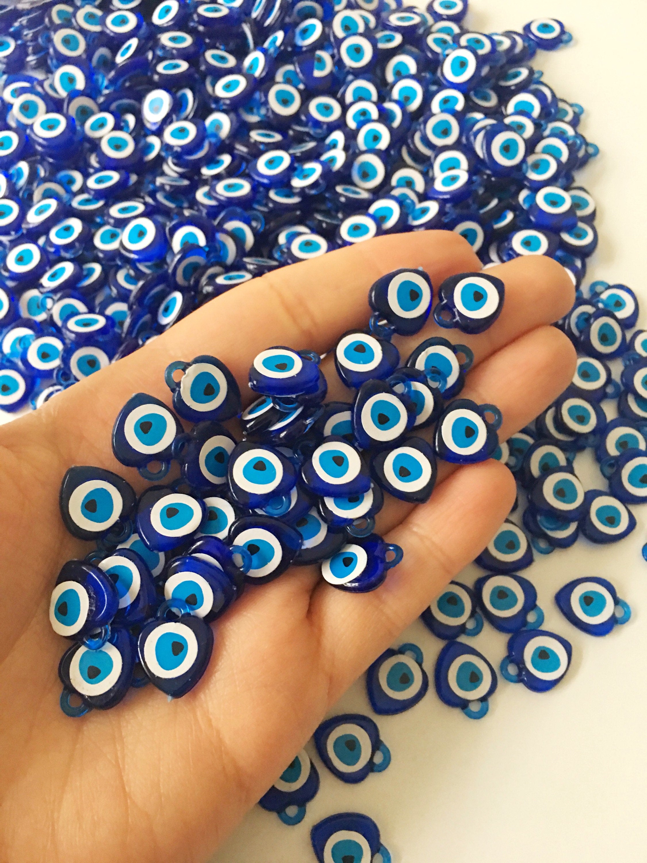 A collection of 100 blue evil eye charms made from resin, showcasing their vibrant color and intricate design, perfect for wedding and party favors.