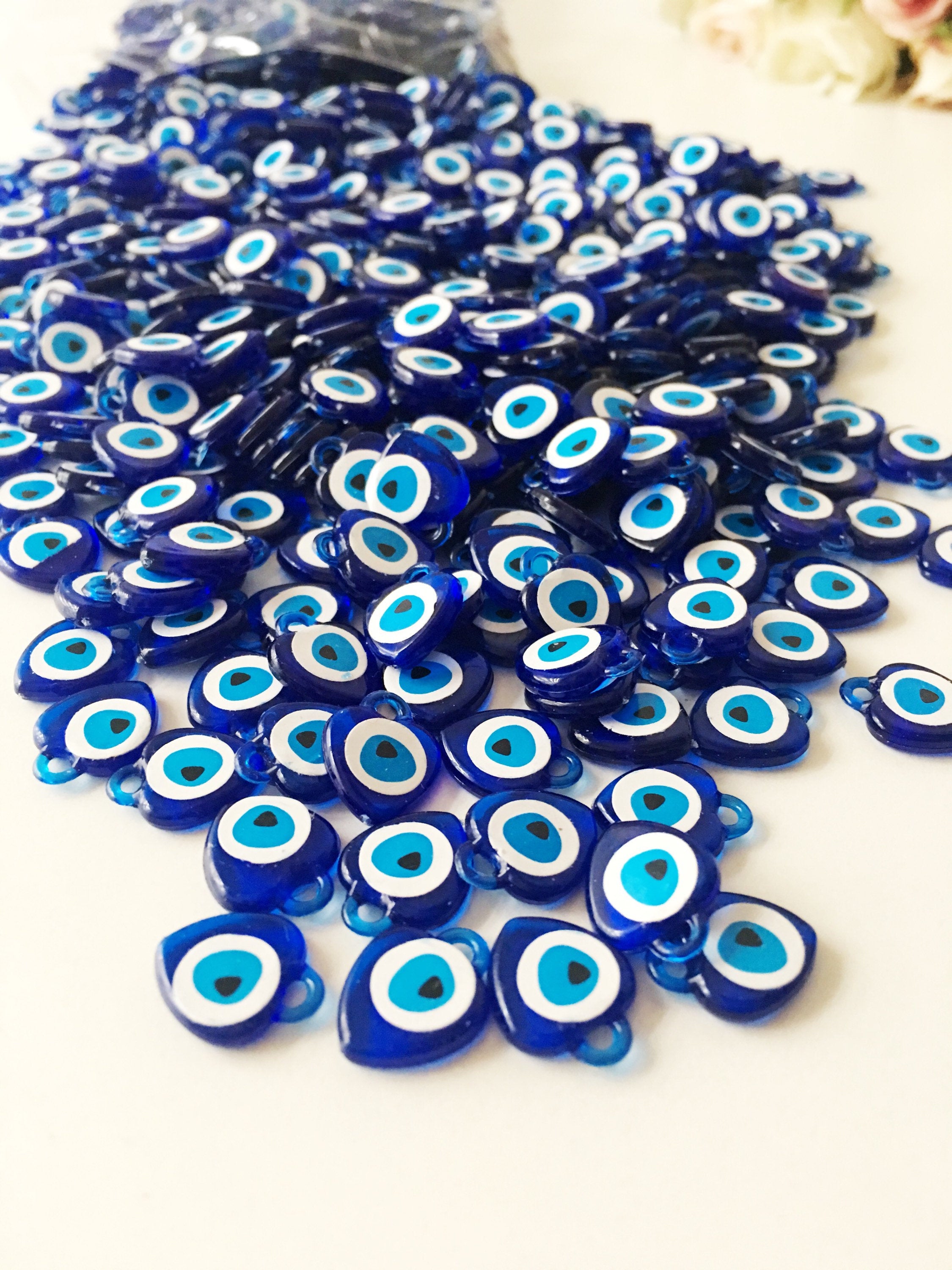 A collection of 100 blue evil eye charms made from resin, showcasing their vibrant color and intricate design, perfect for wedding and party favors.