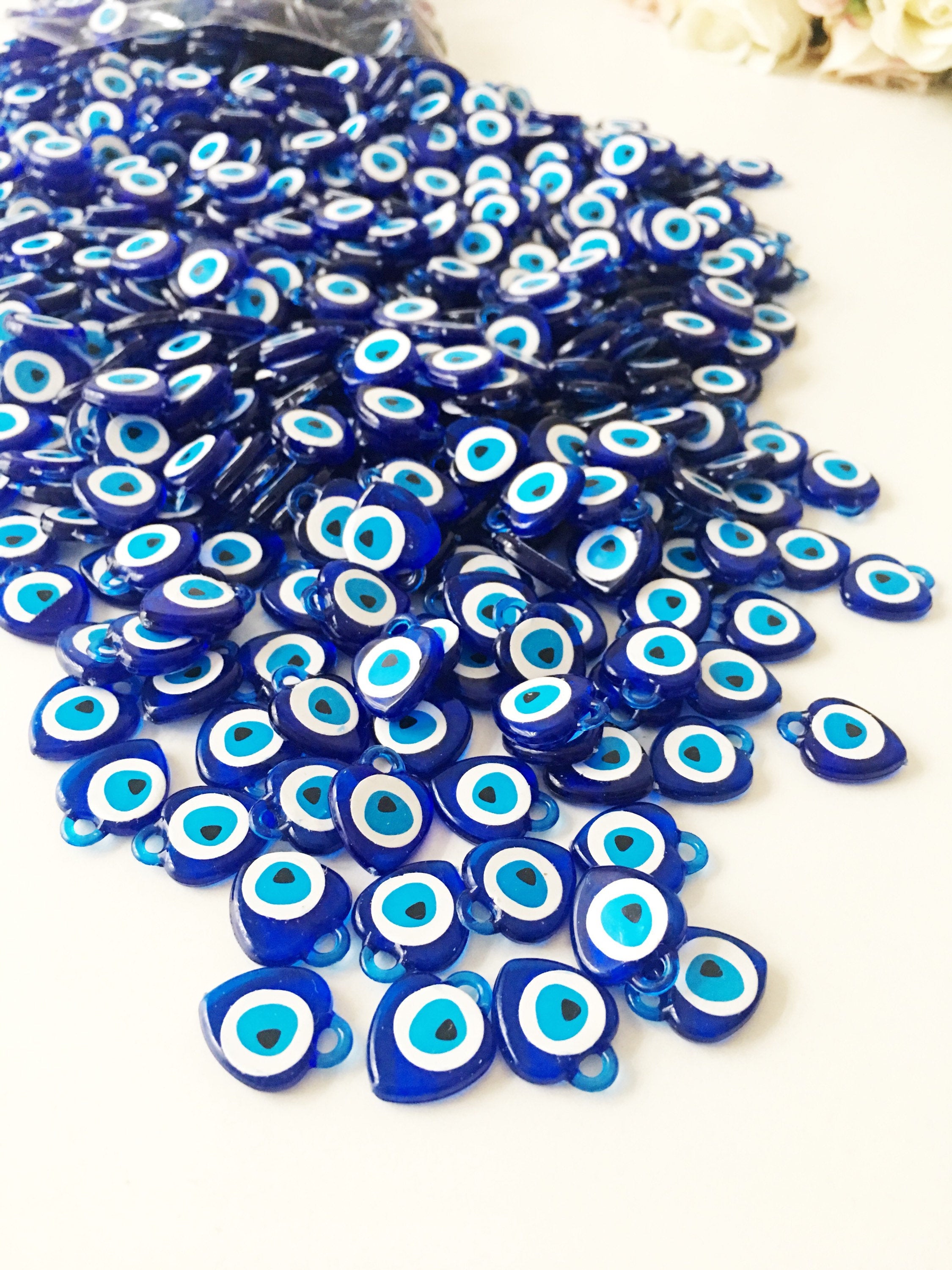 A collection of 100 blue evil eye charms made from resin, showcasing their vibrant color and intricate design, perfect for wedding and party favors.